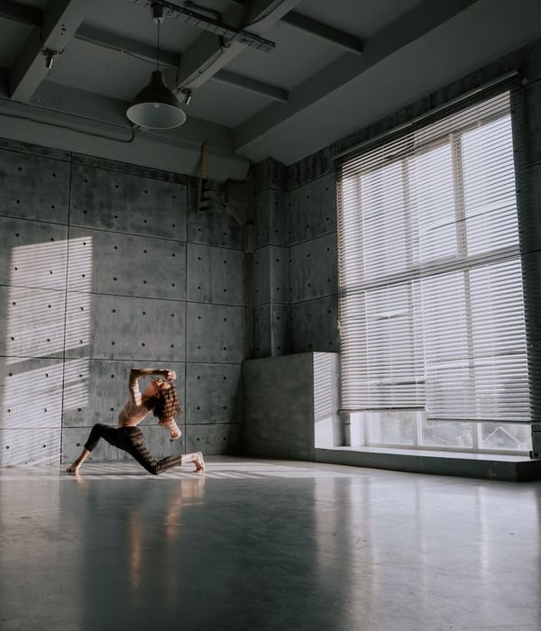 Woman in a light-filled room performing a gentle, flowing movement exercise.